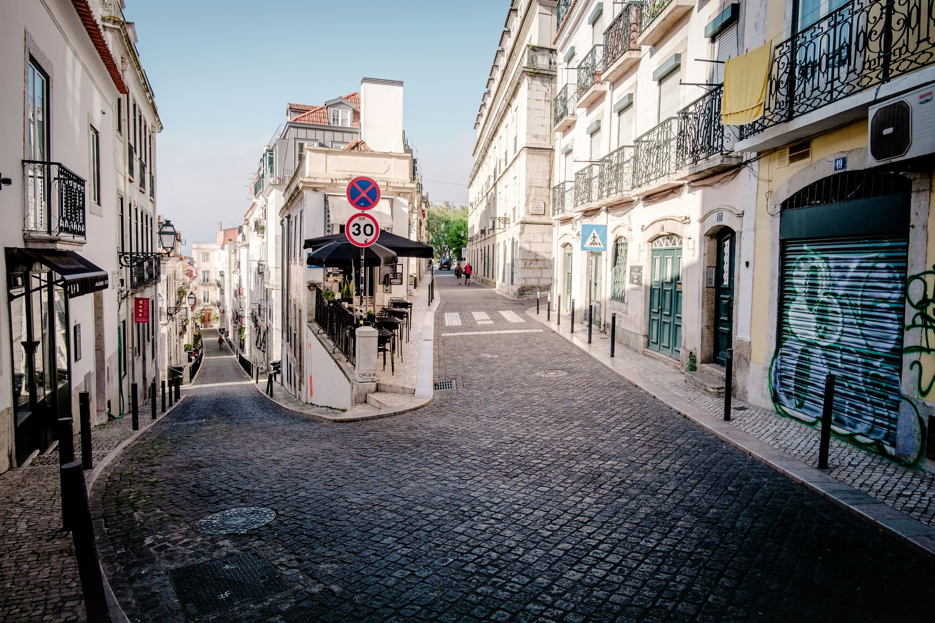 Rua em calçada e paralelepípedos entre edifícios, em Lisboa